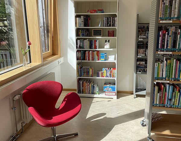 Bücherregal und roter Stuhl in der Ausleihstelle Waldram