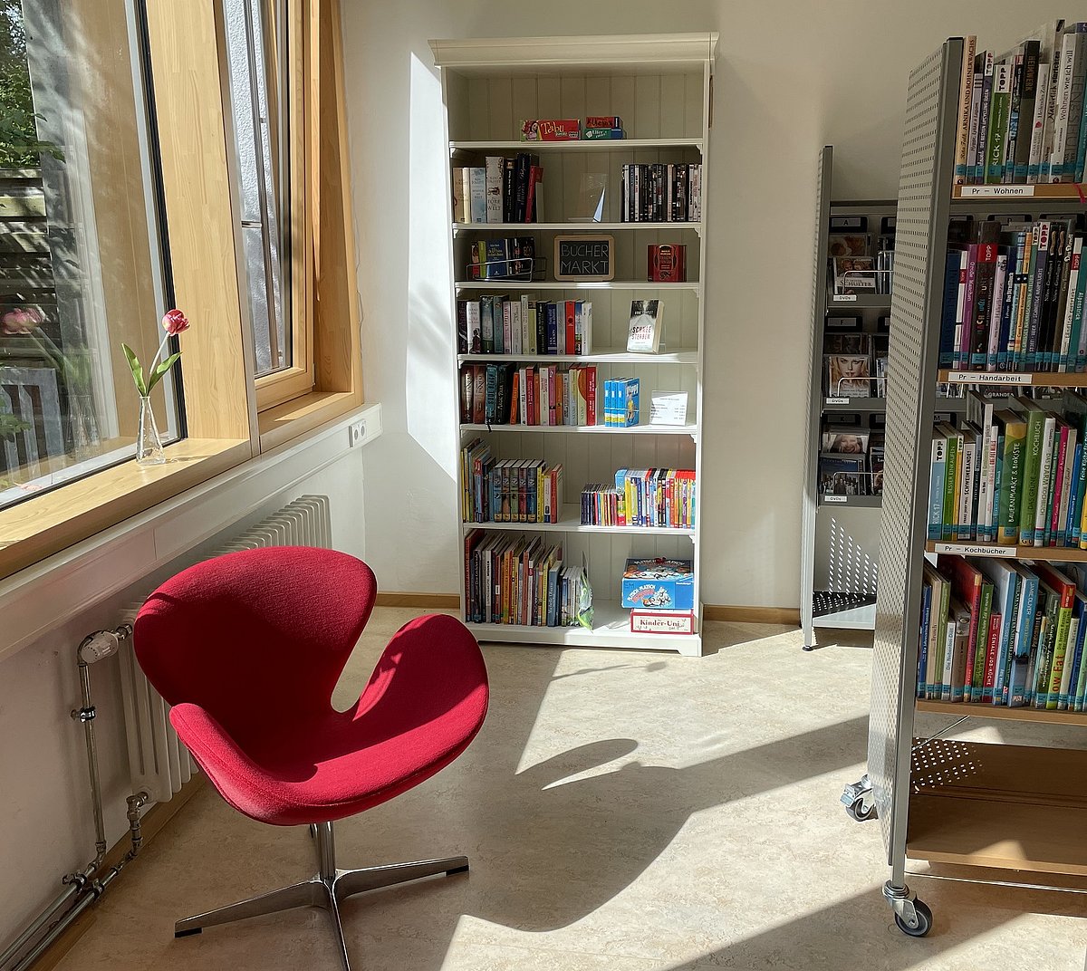 Bücherregal und roter Stuhl in der Ausleihstelle Waldram